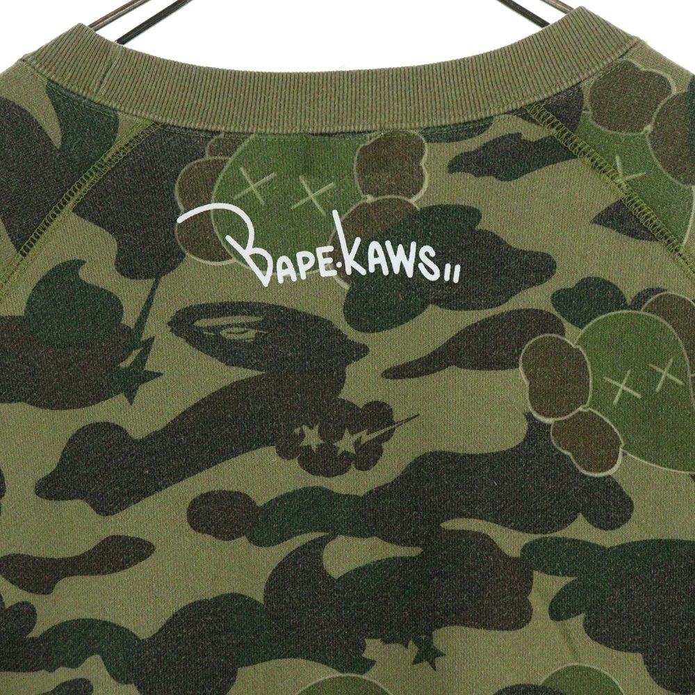 BAPE BY A BATHING APE(ベイプ ア ベイシング エイプ) ×KAWS bendy 1st camo green APE HEAD ×カウズ ベンディー ファーストカモエイプヘッド 総柄クルーネックスウェットトレーナー グリーン